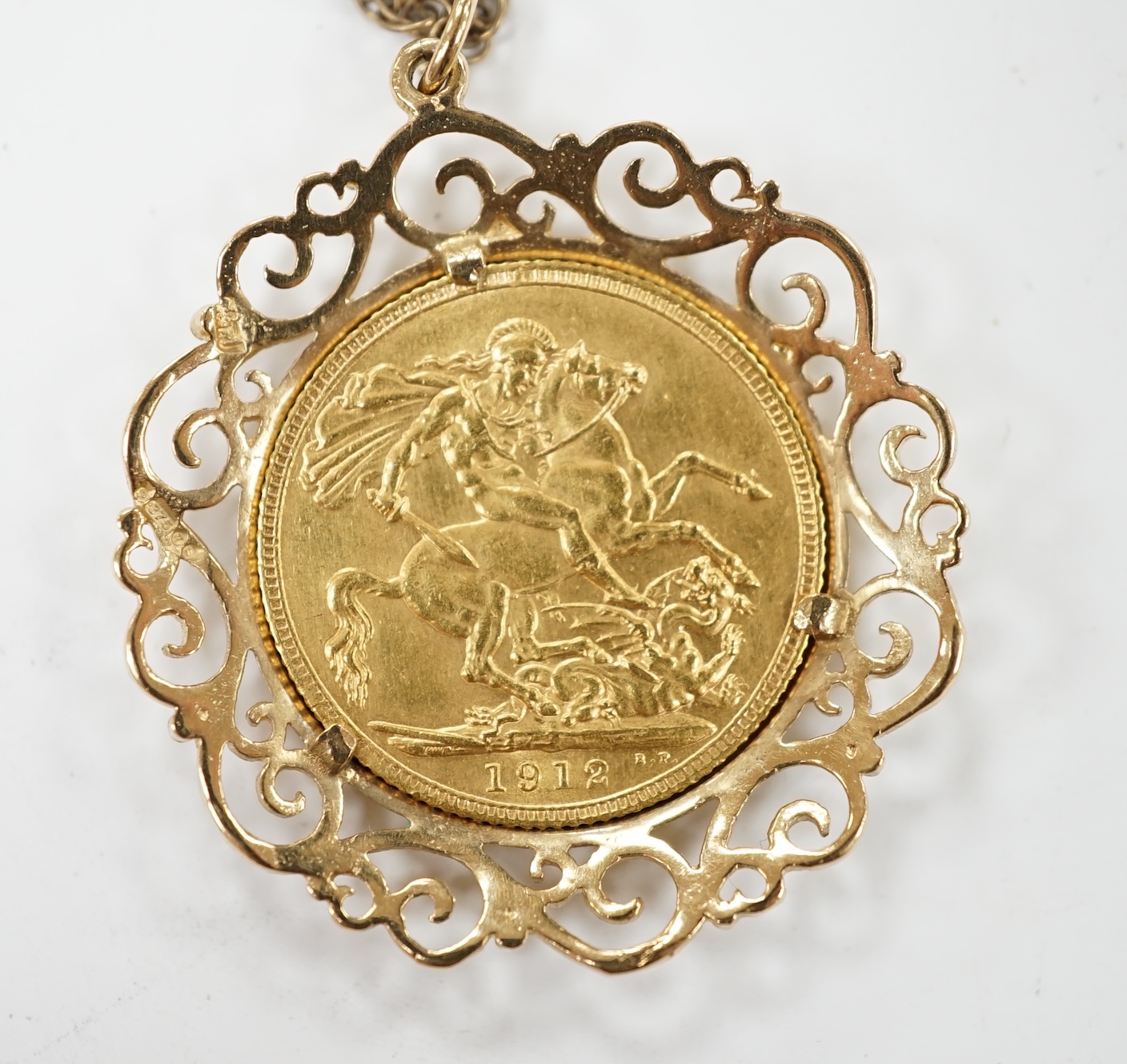 A George V gold sovereign, in a later 9ct gold pendant mount, on a 9ct chain, 63cm, gross weight 16 grams. Condition - fair